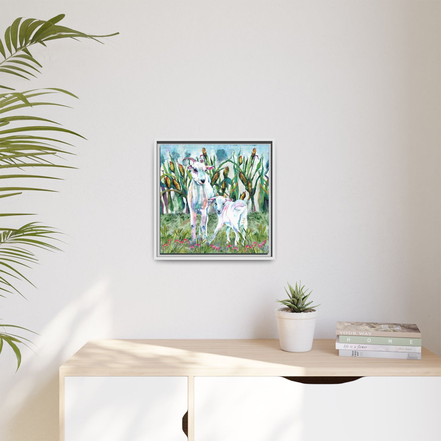Framed artwork of a nature scene with two goats on a wall above a desk.
