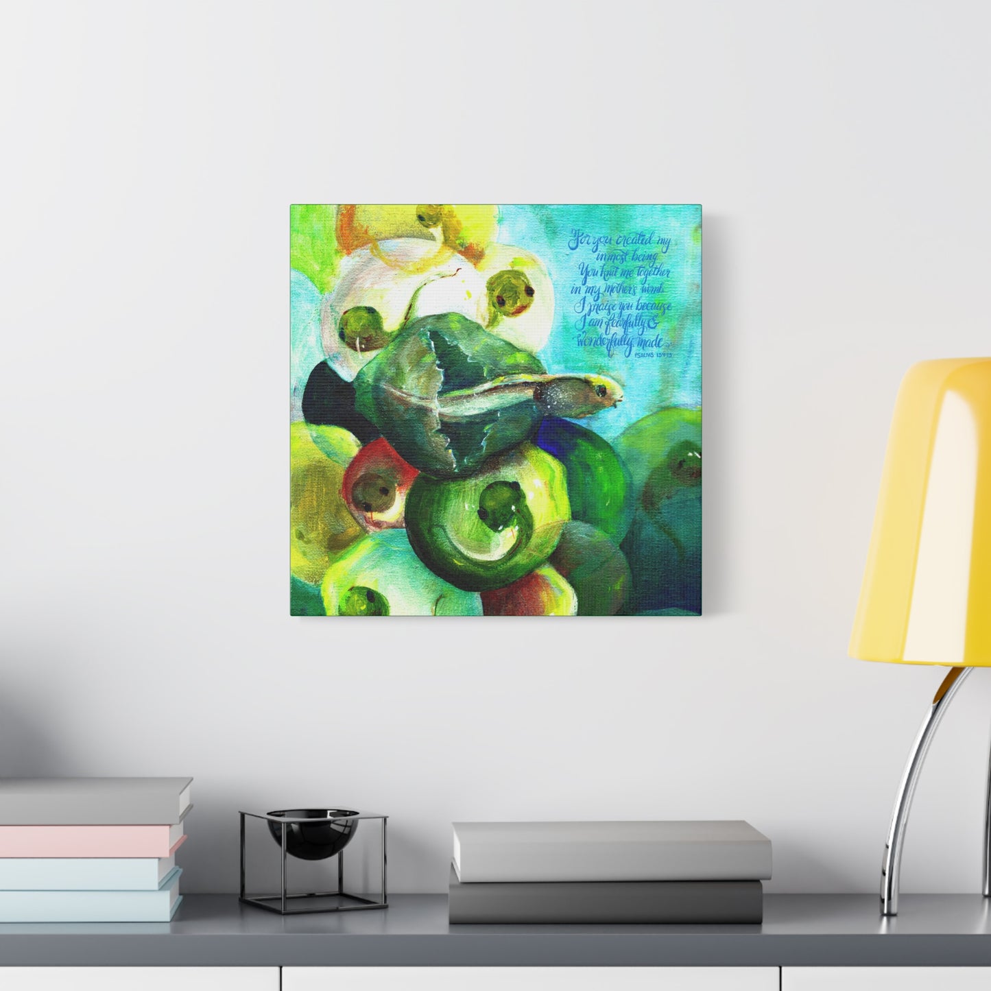 Colorful abstract painting of tadpole and frog eggs with Bible verse Wonderfully made on a wall above a shelf with books and a lamp.