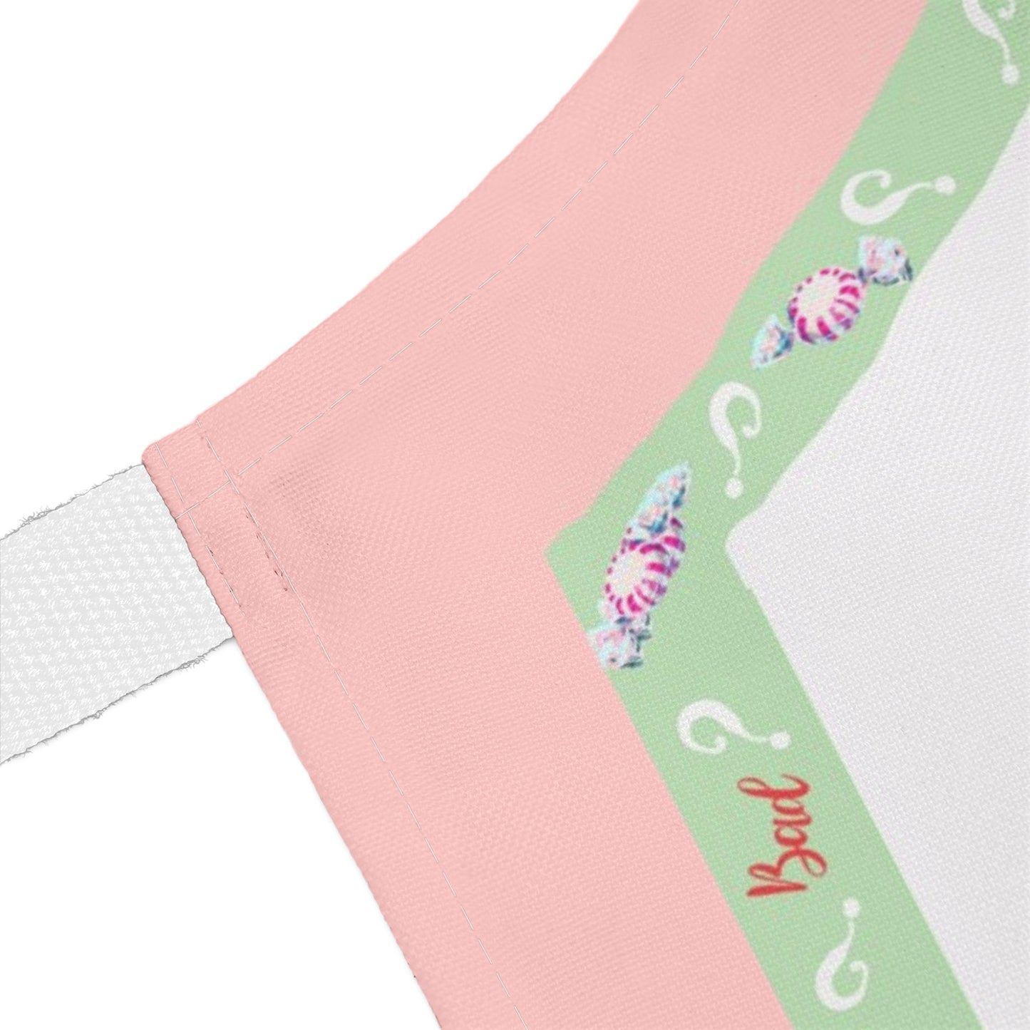 Close-up of a pink and mint green border of Christmas apron featuring question marks and the word 'Bad'.