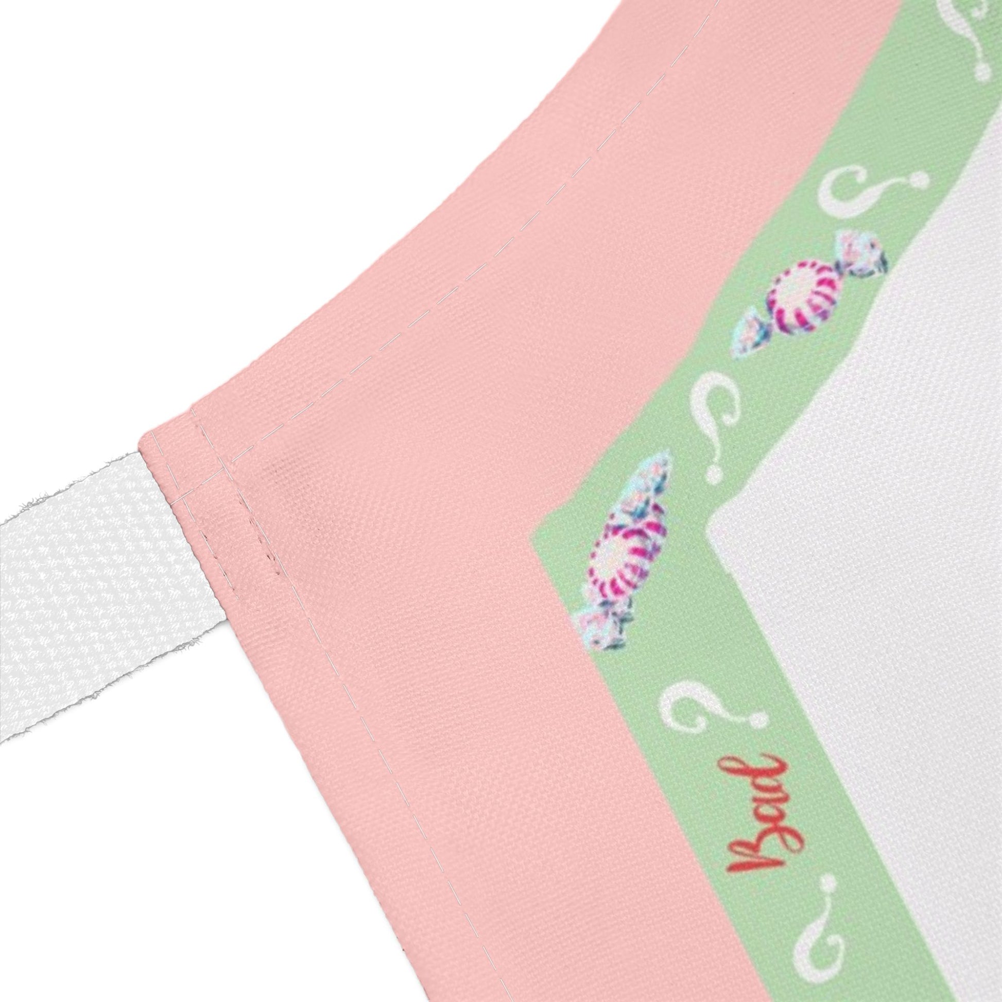 Close-up of a pink and mint green border of Christmas apron featuring question marks and the word 'Bad'.