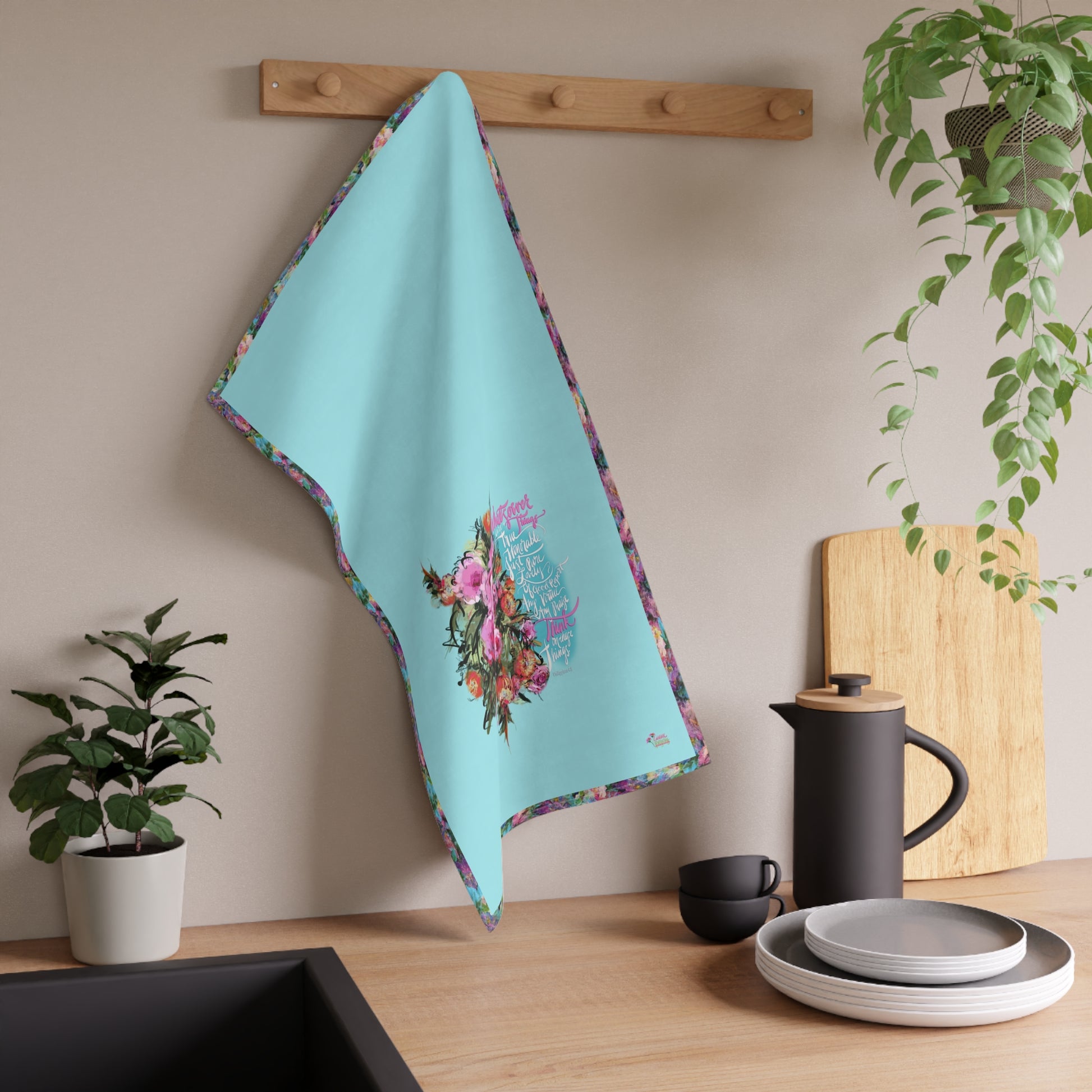 Teal towel with floral design hanging on a wooden rack in a kitchen setting.