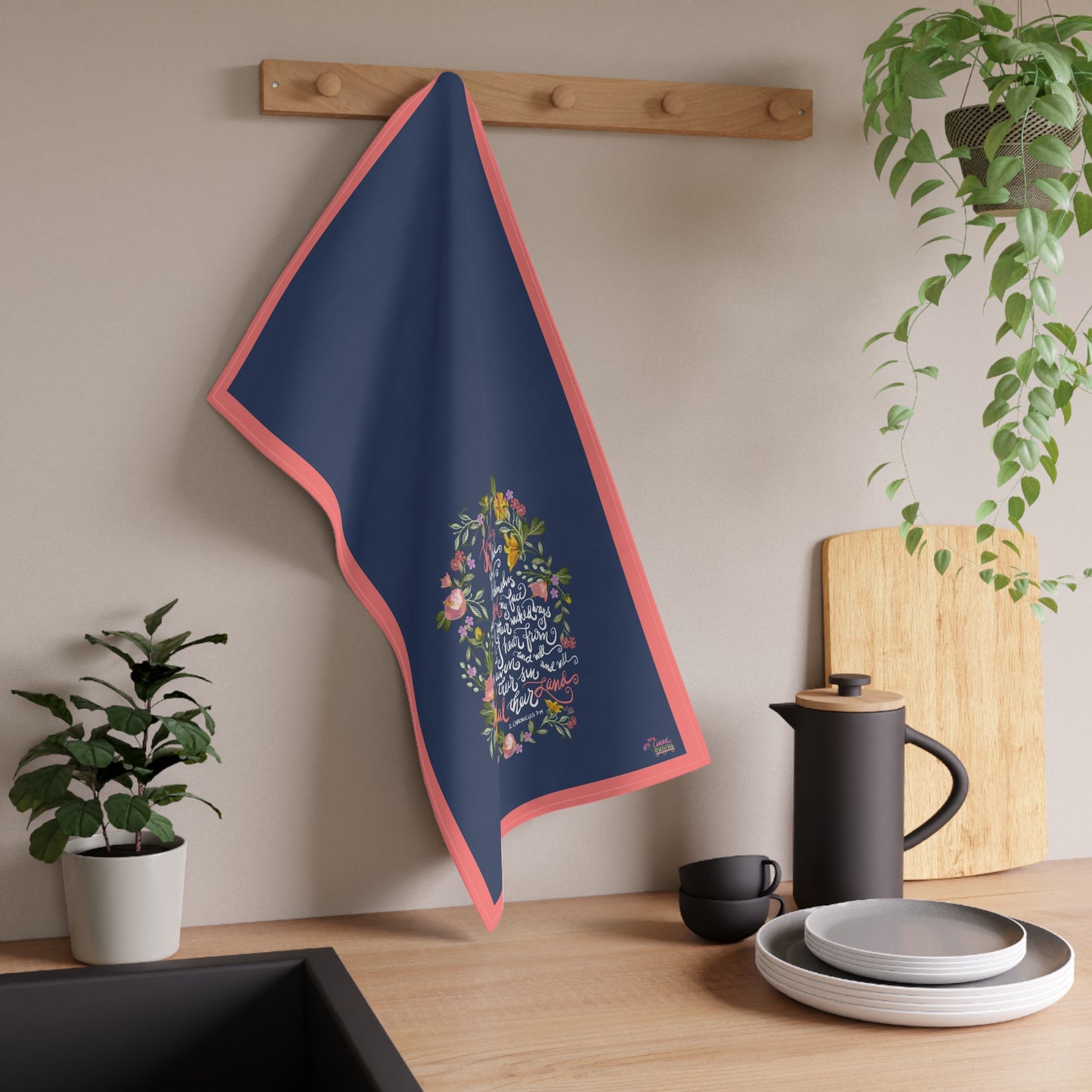 Navy blue tea towel with floral design hanging on a wooden rack in a kitchen setting.