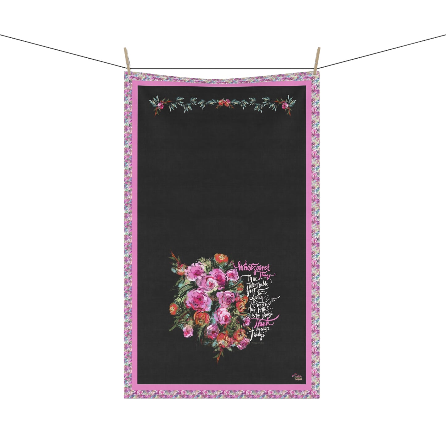 Floral design kitchen tea towel on a black background with pink border and Bible verse "Whatsoever things" hanging on a line.