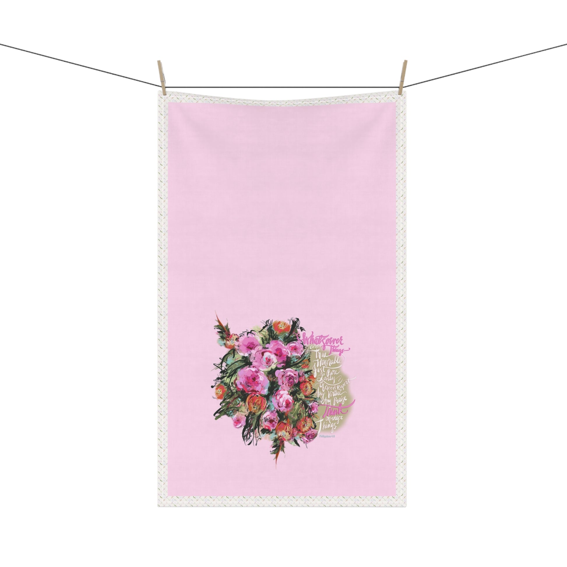 Pink kitchen tea towel with Bible verse "Whatsoever things" and floral design hanging on a line