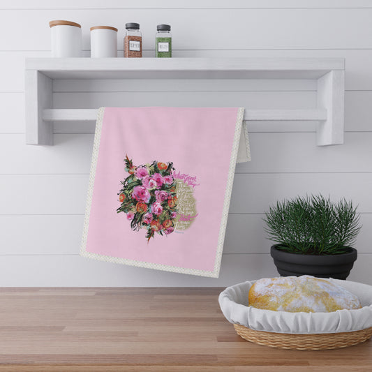 Pink tea towel with Bible verse "Whatsoever things" and floral design hanging on a white shelf in a kitchen setting.