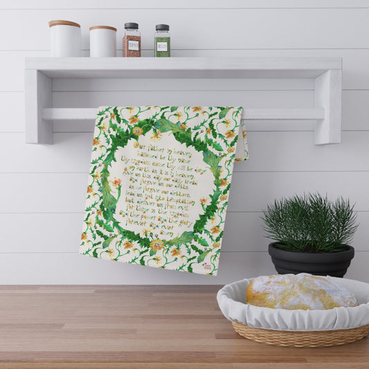 Decorative towel with floral design and the Lord's Prayer text hanging on a wooden shelf in a kitchen setting.