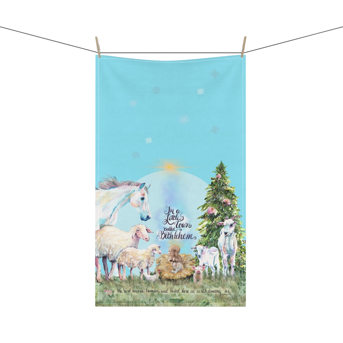 Tea towel with Christmas scene featuring a horse, sheep, goats, a Christmas tree, and baby Jesus in a manger on a blue background.