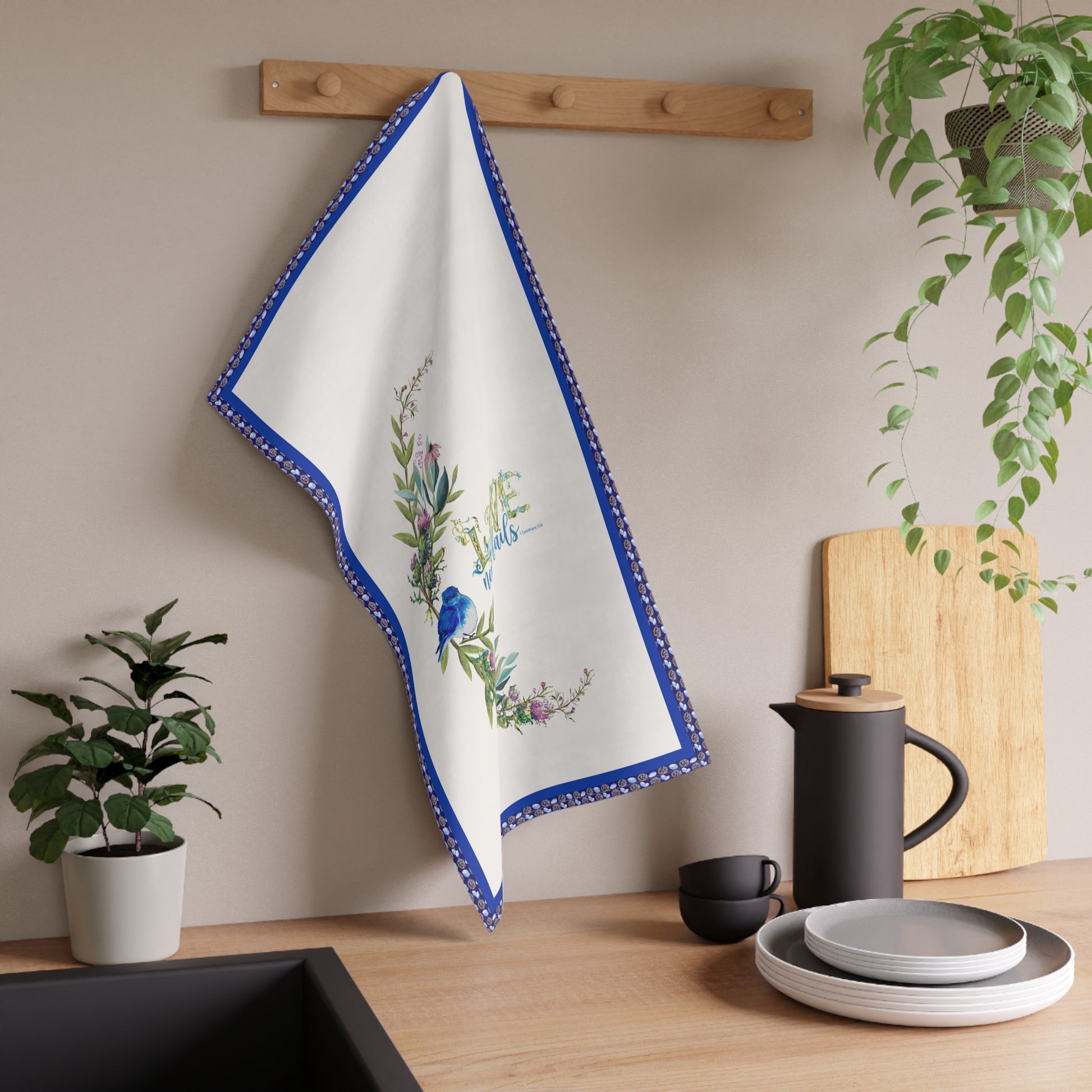 Decorative kitchen towel with floral design hanging on a wooden rack, surrounded by kitchen items.
