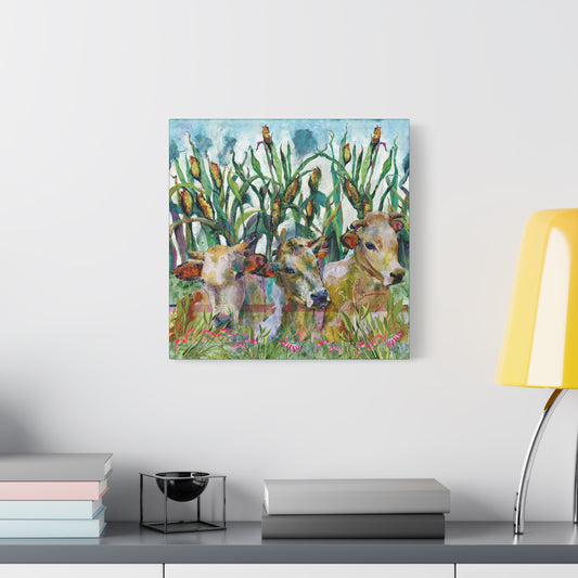 Canvas print of cows in a field with corn on a wall above a desk.