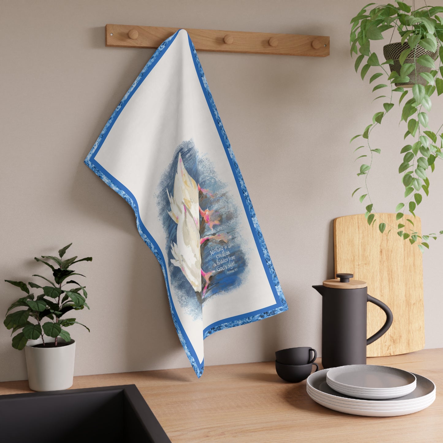 Decorative tea towel with design of two ducks and Bible verse hanging on a wooden rack in a kitchen setting.