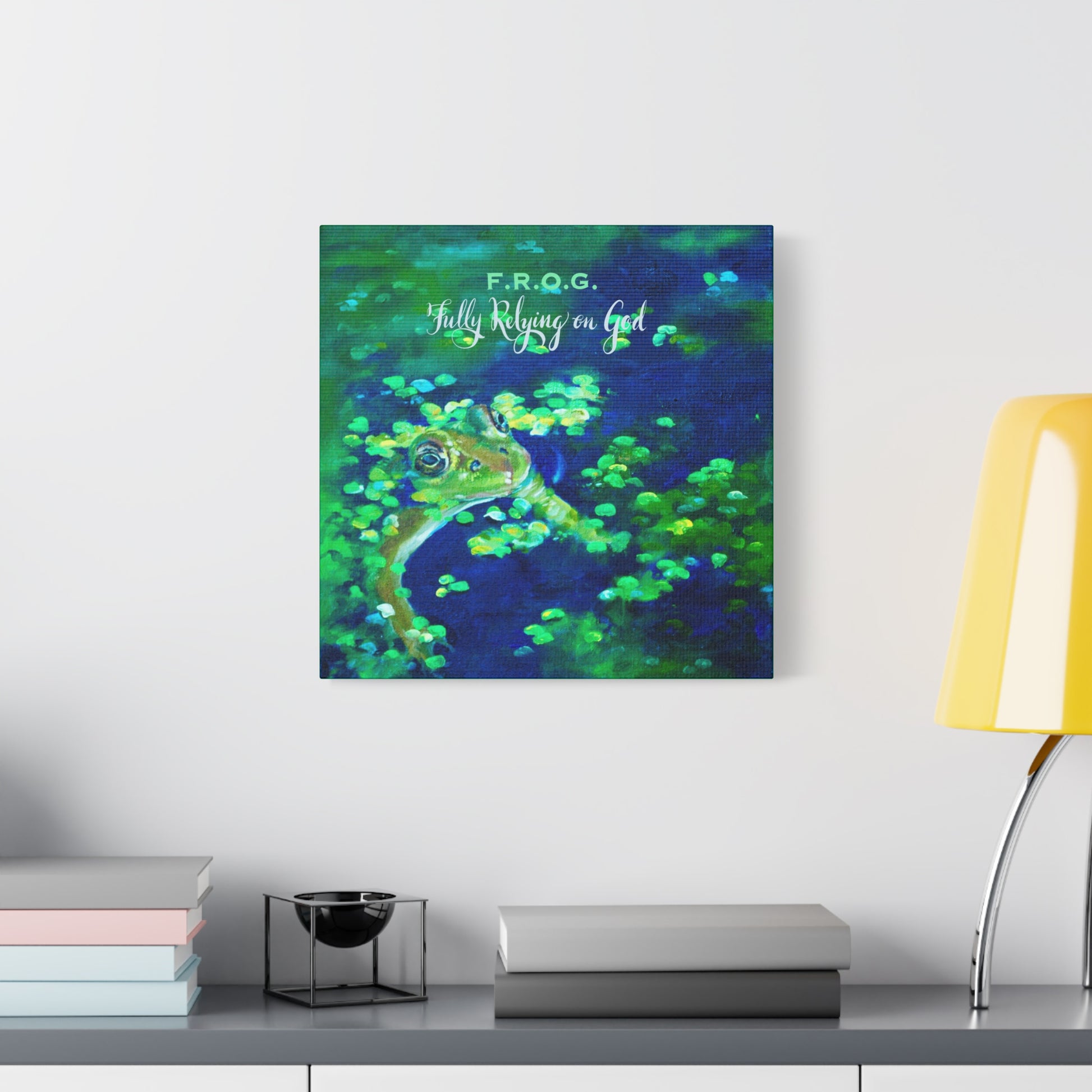 Colorful abstract painting of a frog in a blue pond on a wall above a desk with books and a lamp.
