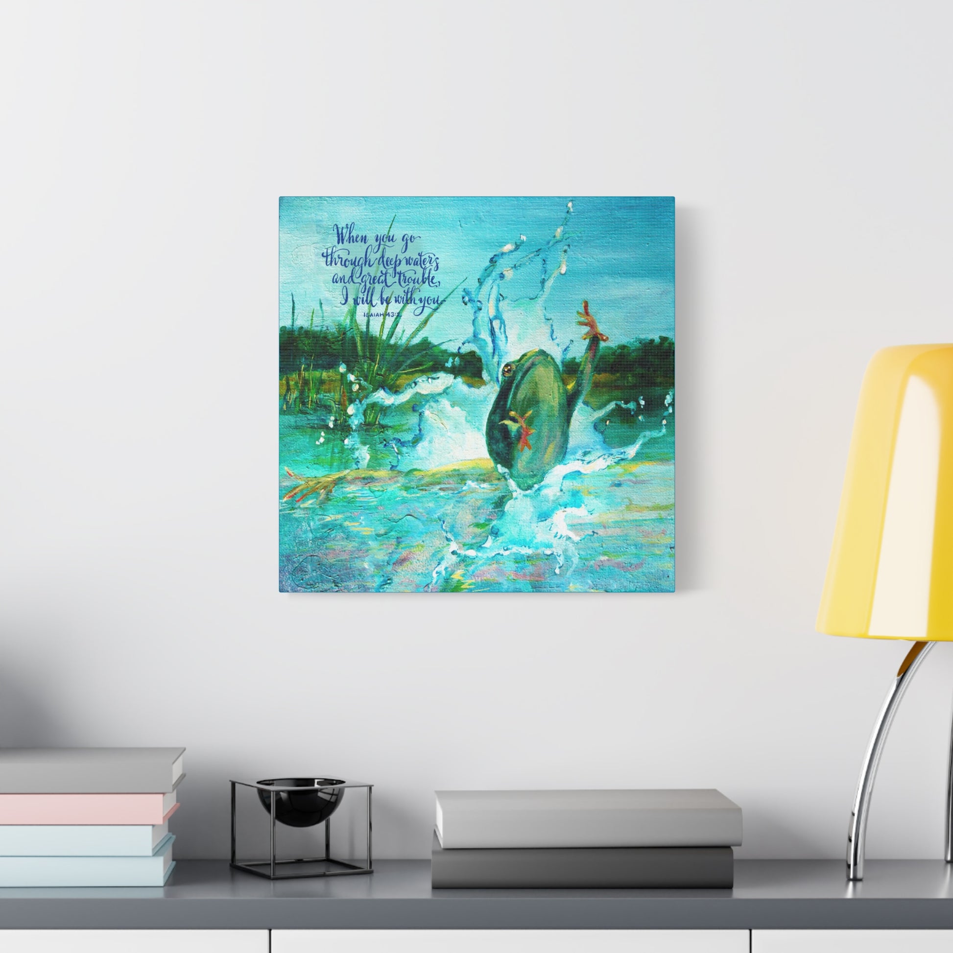 Colorful abstract painting of a frog diving into water with Bible verse about God is with you in troubled waters on a wall above a shelf with books and decor.
