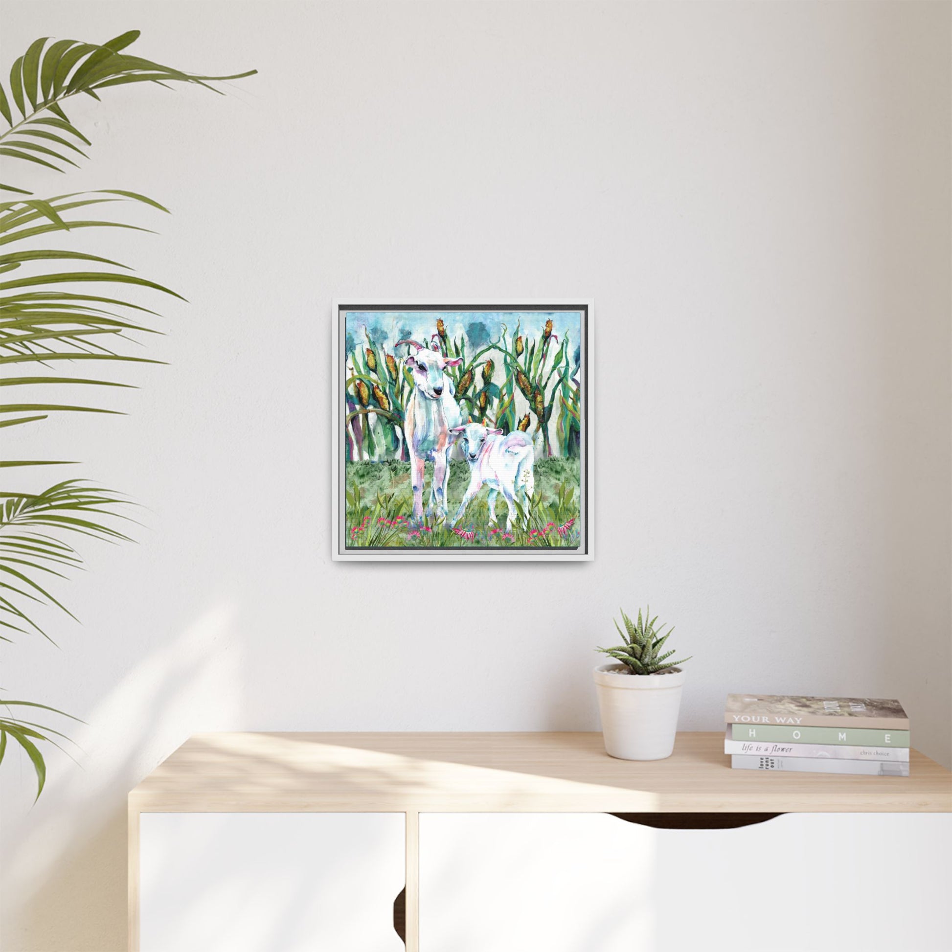 Framed artwork of a nature scene with two goats on a wall above a desk.