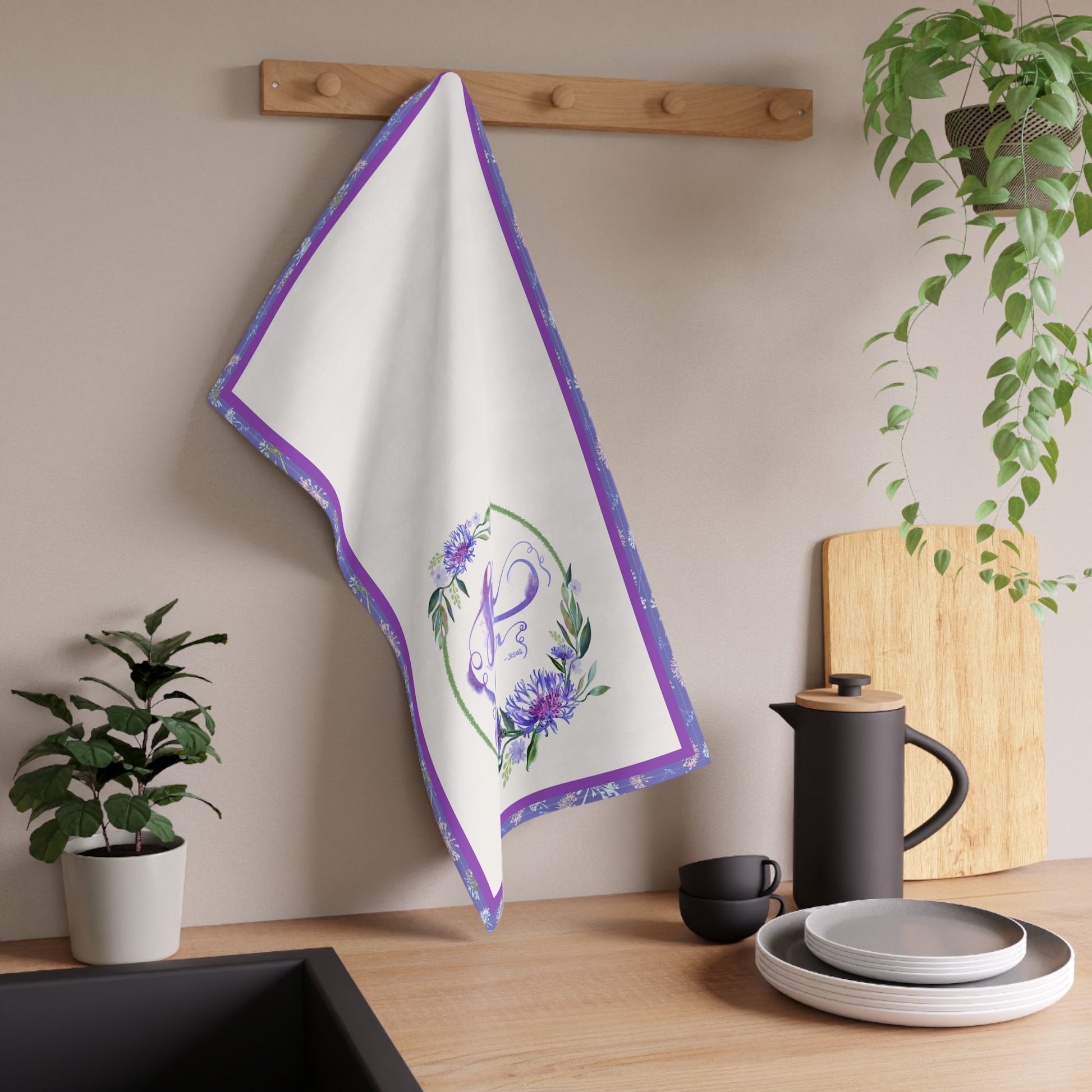 White towel with purple border and floral design hanging on a wooden rack in a kitchen setting.